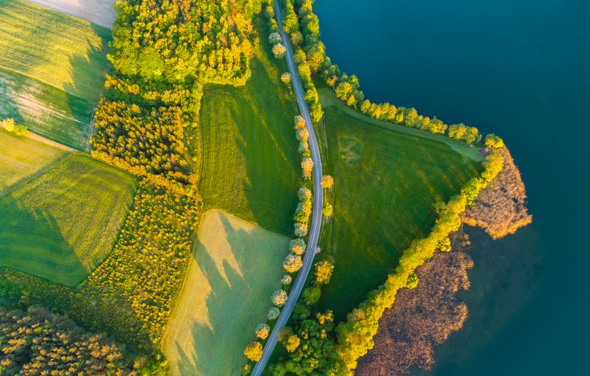 A stunning aerial view of a lush green countryside with winding roads and shimmering blue water.