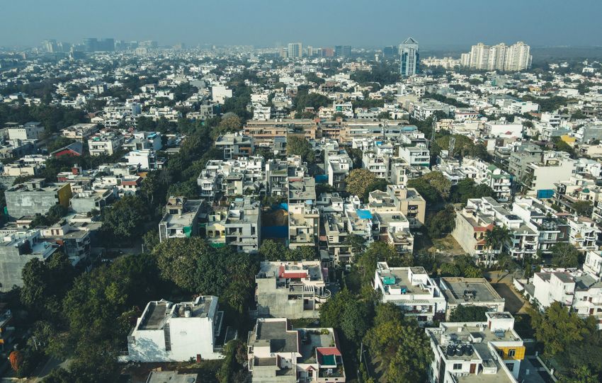 Aerial shot of Gurugram's urban landscape capturing dense residential buildings and city skyline.