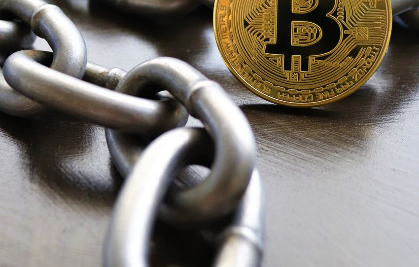 Bitcoin coins intertwined with a metal chain, symbolizing cryptocurrency and blockchain security.