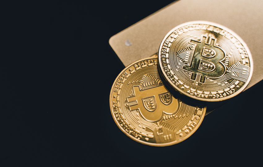 Close-up image of two gold bitcoin coins on a dark background, symbolizing cryptocurrency.