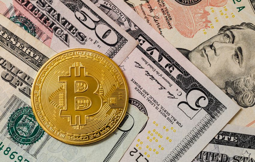 Close-up of a gold Bitcoin coin placed on various US dollar bills, illustrating digital currency concepts.