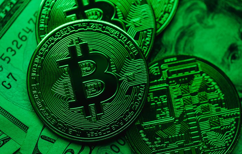 Close-up of Bitcoin coins on paper cash, with a green color tint.
