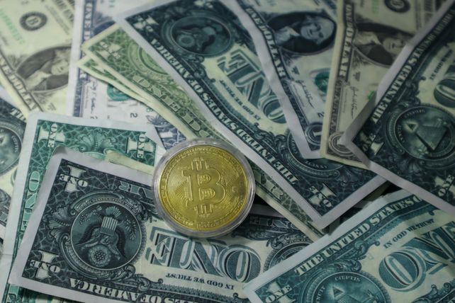 Close-up of Bitcoin cryptocurrency coin on a pile of US dollar banknotes, symbolizing finance and digital currency.