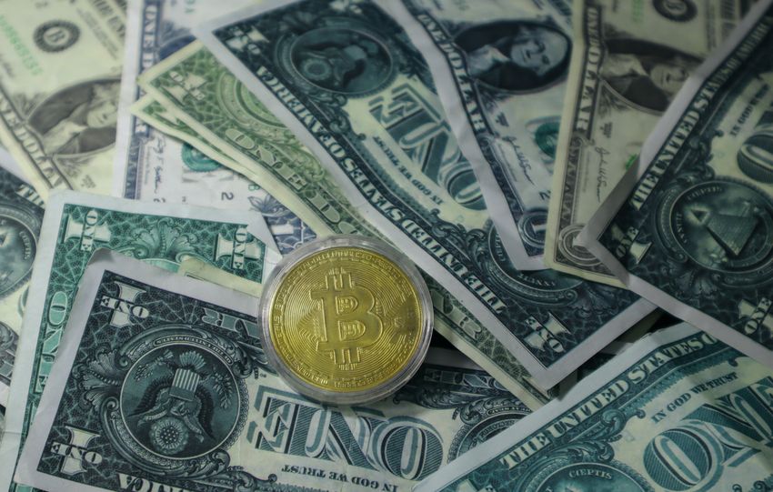 Close-up of Bitcoin cryptocurrency coin on a pile of US dollar banknotes, symbolizing finance and digital currency.