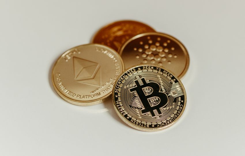 Cryptocurrency coins representing Bitcoin, Ethereum, and Cardano on a white background.