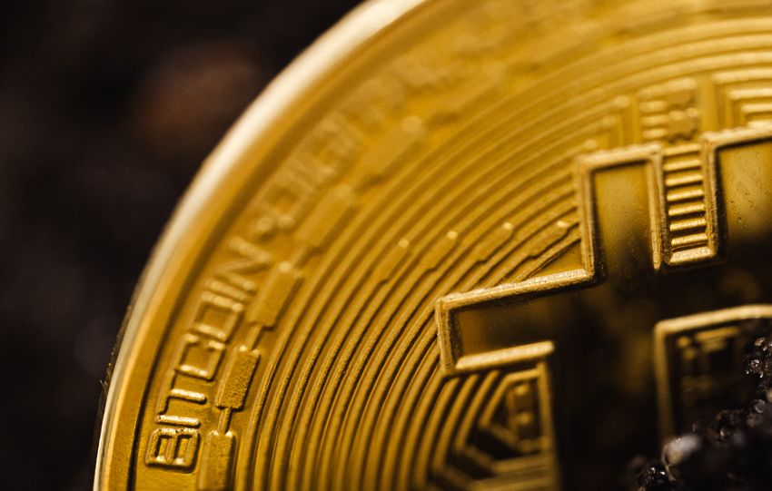 Detailed close-up of a gold Bitcoin partially buried in dark soil, symbolizing digital wealth.