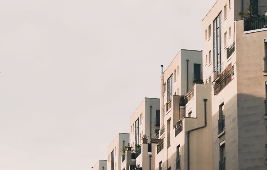 Elegant row of urban apartment buildings under a warm sunset sky.